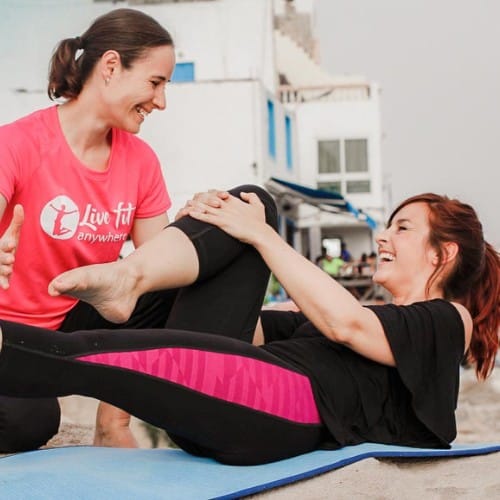 Trainerin macht Pilates Übung mit Kundin