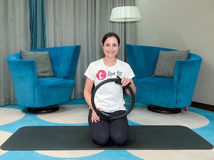 Frau kniet auf einer Pilatesmatte mit einem Pilatesring