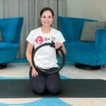 Frau kniet auf einer Pilatesmatte mit einem Pilatesring